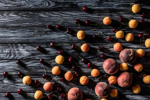 Draufsicht auf Haufen von Kirschen, Aprikosen und Pfirsichen auf Holztisch — Stockfoto