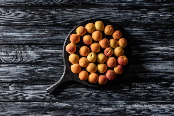 Vue de dessus de pile d'abricots mûrs dans un plateau sur une table en bois — Photo de stock