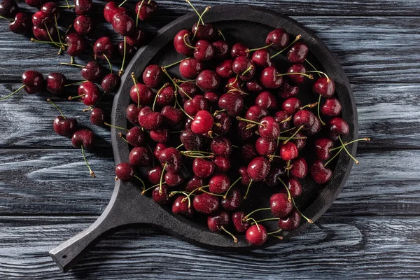 Vue de dessus de pile de cerises mûres rouges dans un plateau sur une table en bois — Photo de stock