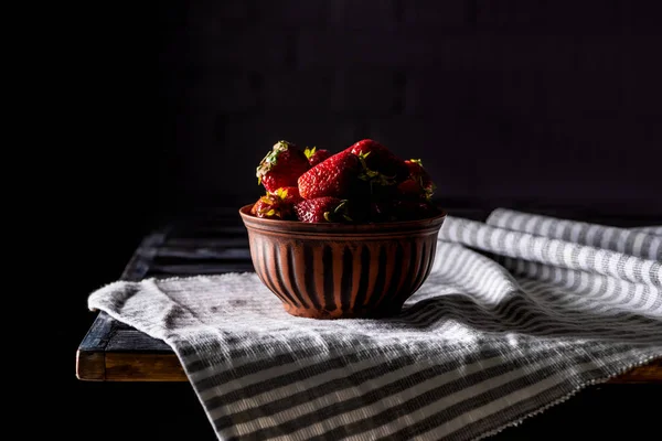 Cerrar vista de tazón con montón de fresas en la mesa de madera en negro - foto de stock