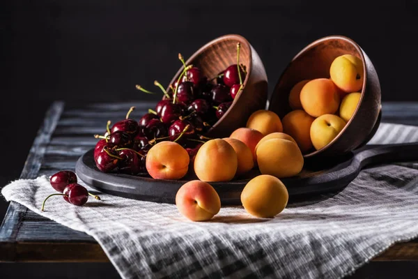 Close up view of bowls with cherries and apricots on tray on wooden table — Stock Photo