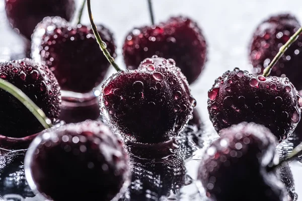 Vista de cerca de cerezas rojas maduras con gotas de agua en la superficie húmeda - foto de stock