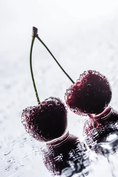 Selektiver Fokus roter reifer Kirschen mit Wassertropfen auf nasser Oberfläche — Stockfoto