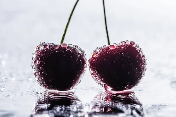 Foco seletivo de cerejas maduras vermelhas com gotas de água na superfície molhada — Fotografia de Stock