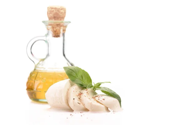 Close up view of oil in glass bottle and mozzarella cheese with basil leaves isolated on white — Stock Photo
