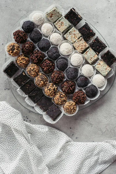 Vue de dessus de divers desserts sucrés disposés sur assiette et nappe sur surface grise — Photo de stock