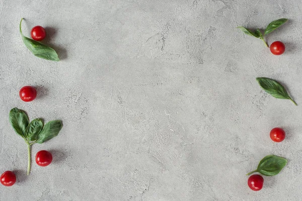Deitado plano com tomate cereja arranjado e espinafre em mesa cinza — Fotografia de Stock