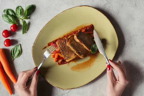 Partial view of woman with fork and knife, paneer in nori seaweed on vegetable julienne and fresh vegetables on grey surface — Stock Photo