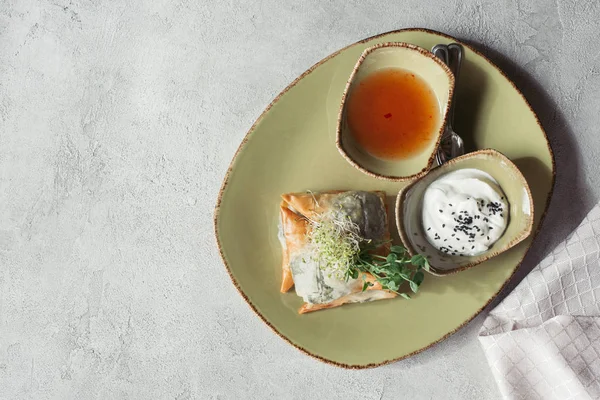 Flat lay with samosas in phyllo dough stuffed with spinach and paneer decorated with germinated seeds of alfalfa and sunflower served on plate on grey surface — Stock Photo