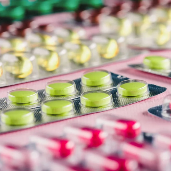 Tiro de close-up de várias pílulas em embalagens de blister em rosa — Fotografia de Stock
