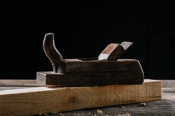 Close up view of vintage woodworker plane and plank isolated on black — Stock Photo