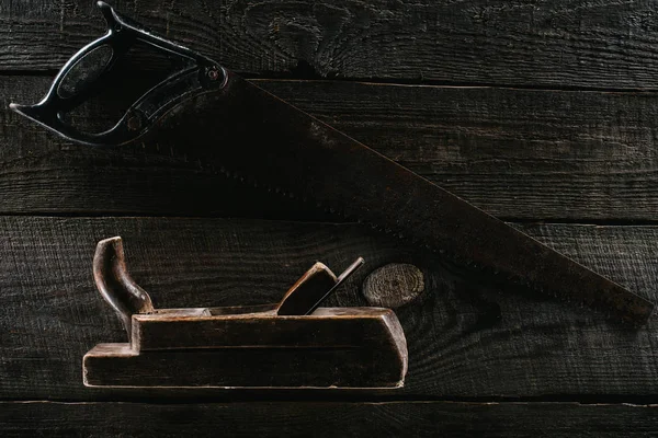 Top view of retro rusty saw and woodworker plane on wooden surface — Stock Photo