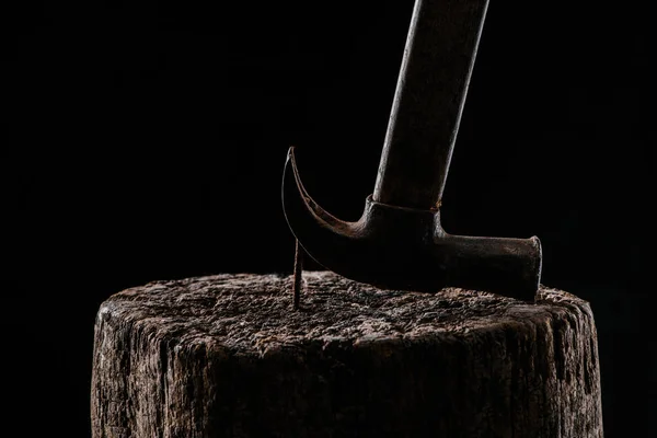 Close up view of vintage rusty hammer and nail in wooden stump isolated on black — Stock Photo