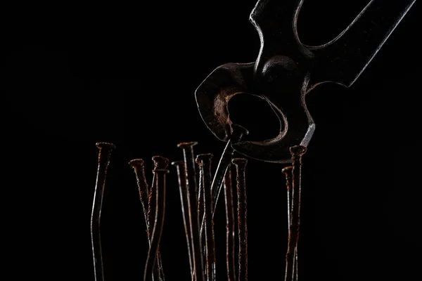 Закрыть вид винтажных ржавых плоскогубцев и ногтей, изолированных на черном — стоковое фото
