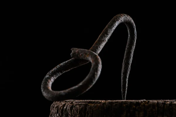 Close up view of vintage hook on wooden stump isolated on black — Stock Photo