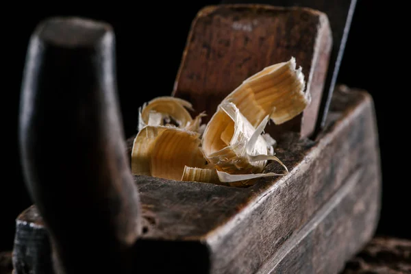 Selektiver Fokus von Vintage-Holzarbeiterhobel und Holzspäne isoliert auf schwarz — Stockfoto