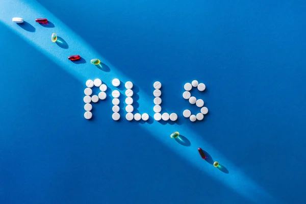 Vue du dessus des pilules de lettrage par des comprimés blancs sur fond bleu avec la lumière du soleil — Photo de stock
