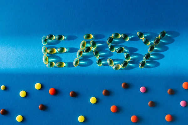 Top view of lettering easy by pills near various tablets on blue background with sunlight — Stock Photo