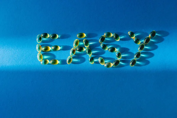Vista superior de letras fácil por pílulas em fundo azul com luz solar — Fotografia de Stock