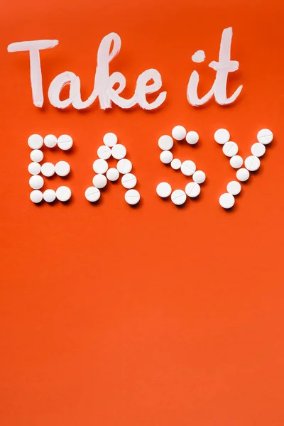 Vista superior de letras ter mais fácil feito por pílulas brancas no fundo vermelho — Fotografia de Stock