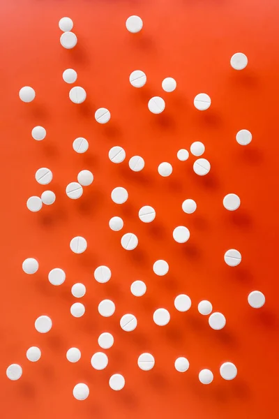 Top view of pile of white tablets on red background — Stock Photo