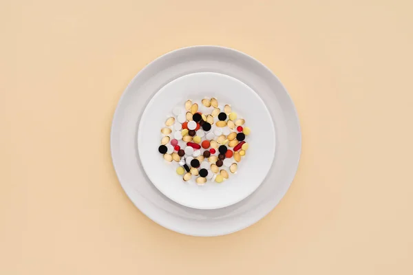 Vista dall'alto del piatto con varie pillole su sfondo beige — Foto stock