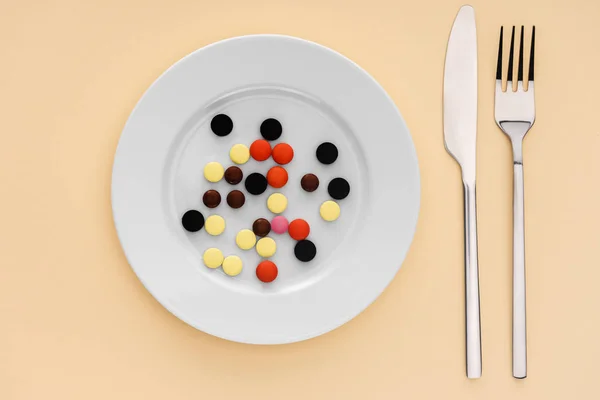 Top view of fork, knife and plate with various pills on beige background — Stock Photo