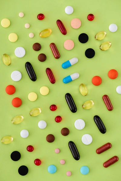 Vue du dessus de diverses pilules disposées sur fond vert — Photo de stock
