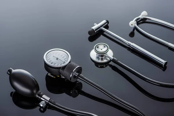 Close up view of device for measuring pressure, reflex hammer and stethoscope on glass surface — Stock Photo