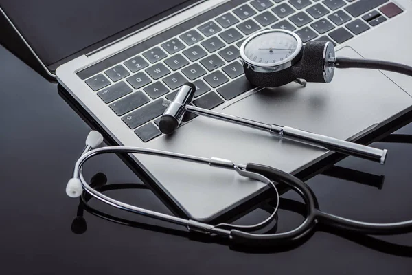 Close up view of stethoscope, tonometer, reflex hammer and laptop on glass surface — Stock Photo