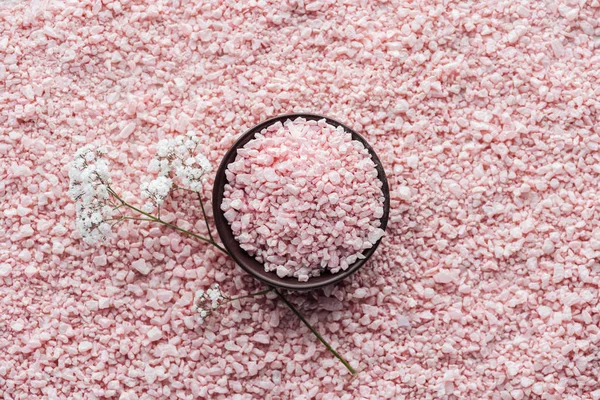 Top view of pink sea salt in bowl and beautiful small white flowers — Stock Photo