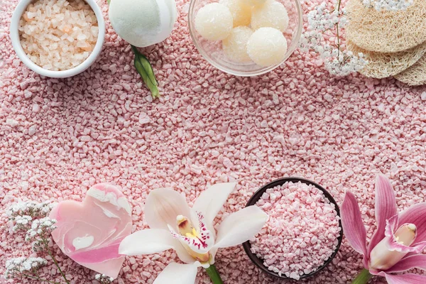 Vista superior de hermosas flores de orquídea, jabón hecho a mano, esponjas y sal marina rosa - foto de stock