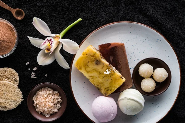 Top view of handmade soaps, sea salt and orchid flower on black — Stock Photo