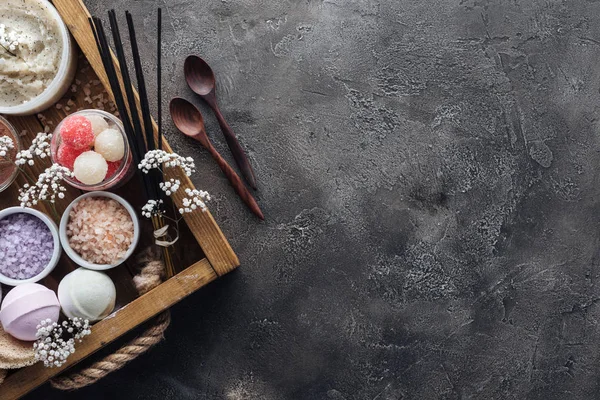 Vue de dessus des accessoires de spa et de soins du corps en boîte et cuillères en bois sur fond gris — Photo de stock