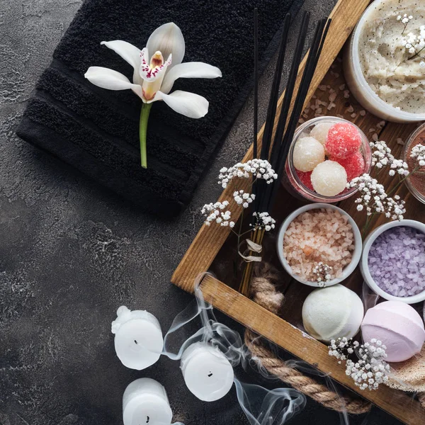 Vista dall'alto di bella orchidea, asciugamano, candele e accessori per la cura del corpo su grigio — Foto stock