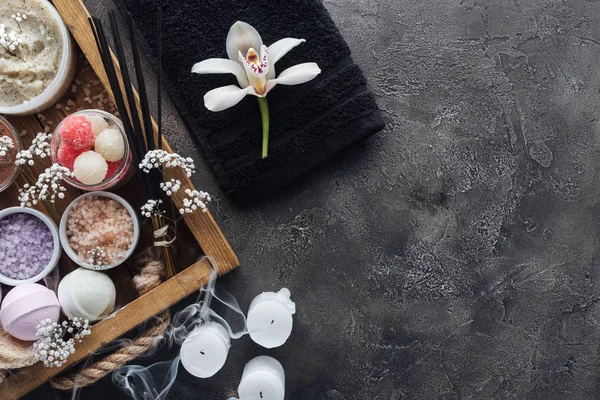 Вид зверху на красиву орхідею, рушник, свічки та спа-аксесуари на сірому — стокове фото