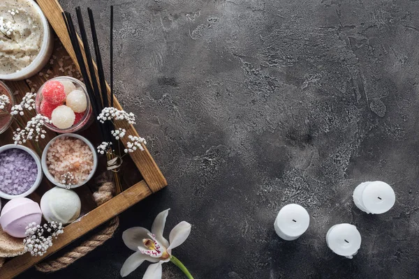 Vista dall'alto di accessori spa e bagno in scatola di legno, orchidee e candele su sfondo grigio — Foto stock