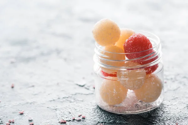 Vue rapprochée des balles de gommage faites maison dans un récipient en verre sur fond gris — Photo de stock