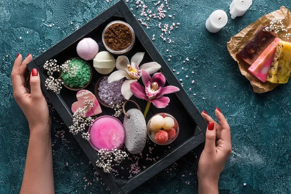 Tiro recortado de mãos humanas e caixa com acessórios de spa orgânicos e flores — Fotografia de Stock