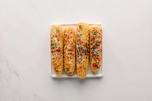 Top view of delicious grilled corn with salt on plate on marble table — Stock Photo