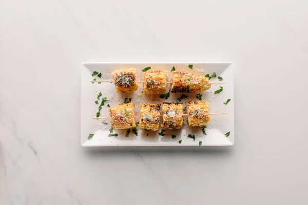 Top view of delicious grilled corn and parsley on plate on marble table — Stock Photo