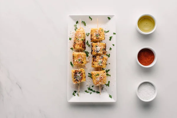 Top view of grilled corn on plate with salt, oil and chili spice on marble table — Stock Photo