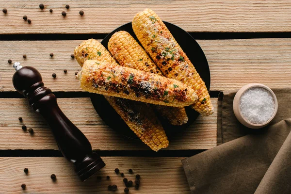 Vue du dessus du maïs grillé, du moulin à poivre et du sel sur la table en bois — Photo de stock