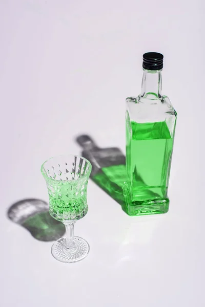 Crystal glass and bottle of absinthe on white — Stock Photo