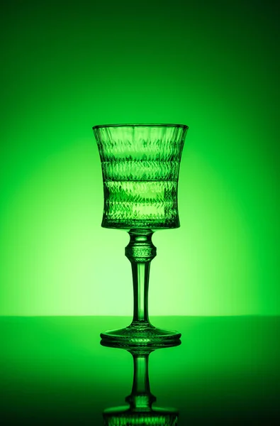 Vidrio de plomo de absenta sobre superficie reflectante y fondo verde oscuro - foto de stock