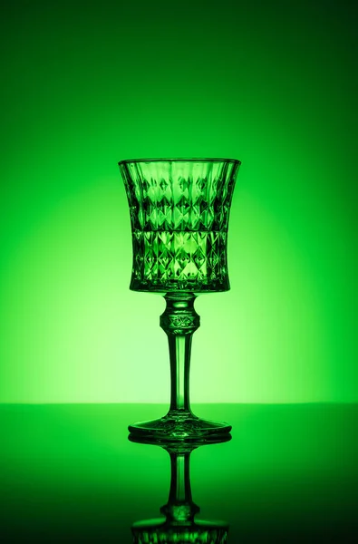 Cristal de absenta sobre superficie reflectante y fondo verde oscuro - foto de stock