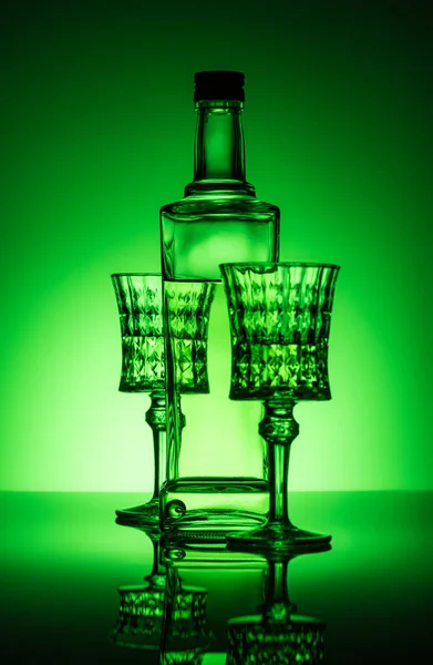 Bouteille d'absinthe avec verres en plomb sur la surface du miroir et fond vert foncé — Photo de stock