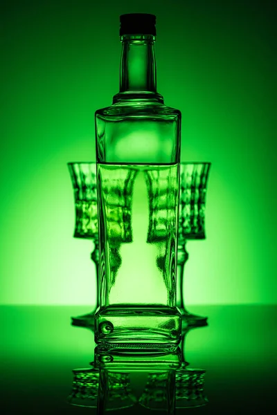 Flasche Absinth mit Brille auf Spiegeloberfläche und dunkelgrünem Hintergrund — Stockfoto