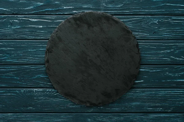 Top view of round stone cutting board on green wooden tabletop — Stock Photo