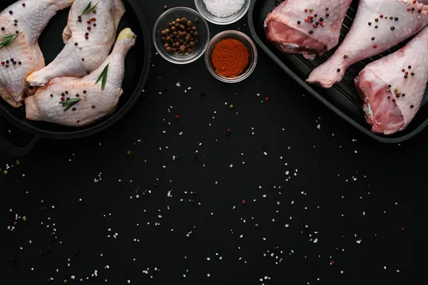 Flat lay with turkey and chicken legs on grill pans with spices on black table — Stock Photo